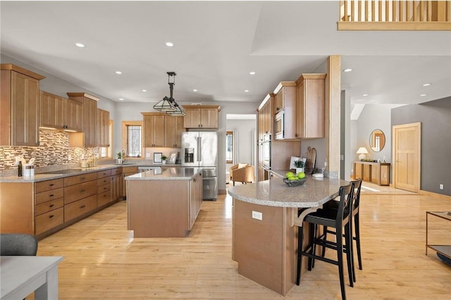 kitchen with a breakfast bar area, stainless steel appliances, decorative light fixtures, a center island, and kitchen peninsula