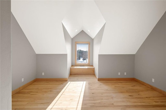 additional living space with light hardwood / wood-style flooring and lofted ceiling