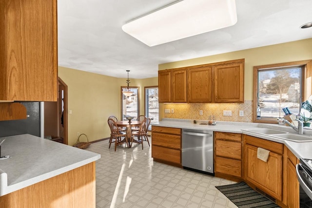 kitchen featuring sink, pendant lighting, plenty of natural light, stainless steel dishwasher, and decorative backsplash