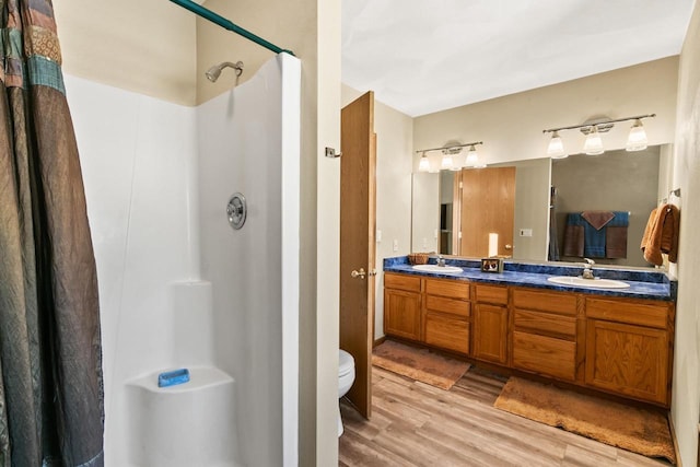 bathroom with toilet, hardwood / wood-style flooring, walk in shower, and vanity