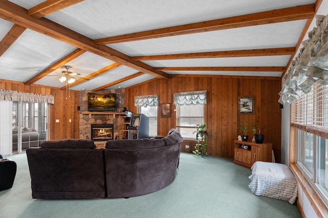 living room with a fireplace, wooden walls, vaulted ceiling with beams, ceiling fan, and carpet flooring