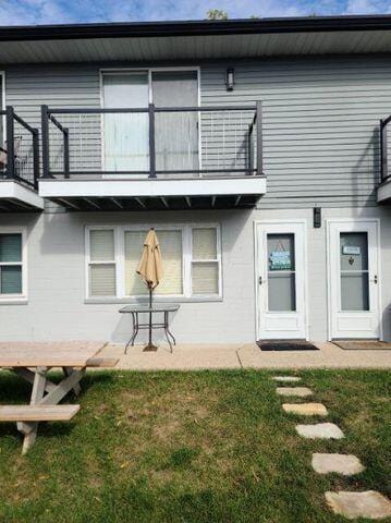 rear view of house featuring a patio, a yard, and a balcony