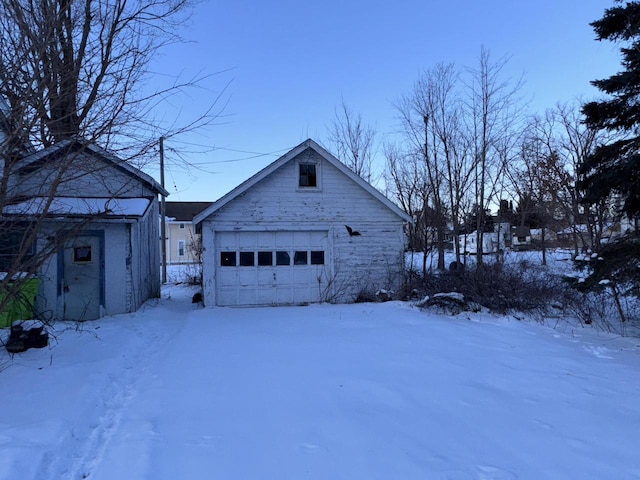 snow covered property featuring an outbuilding and a garage