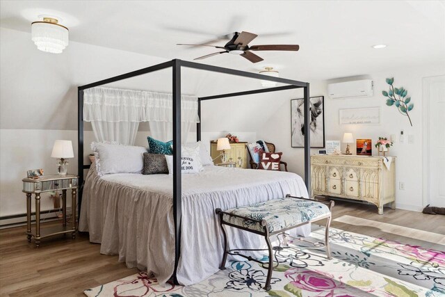 bedroom featuring ceiling fan, vaulted ceiling, wood finished floors, and a wall mounted AC