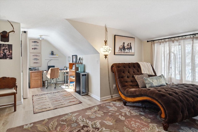 home office featuring vaulted ceiling, light wood-style flooring, a textured ceiling, and baseboards