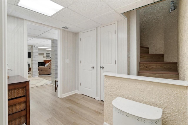 bathroom with wood finished floors, baseboards, visible vents, a fireplace, and a drop ceiling