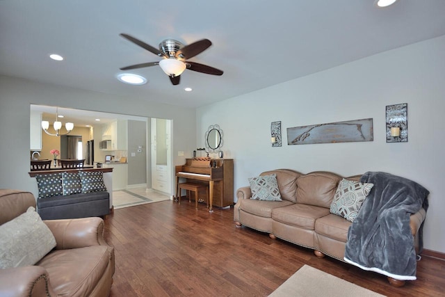 living room featuring ceiling fan with notable chandelier and wood-type flooring