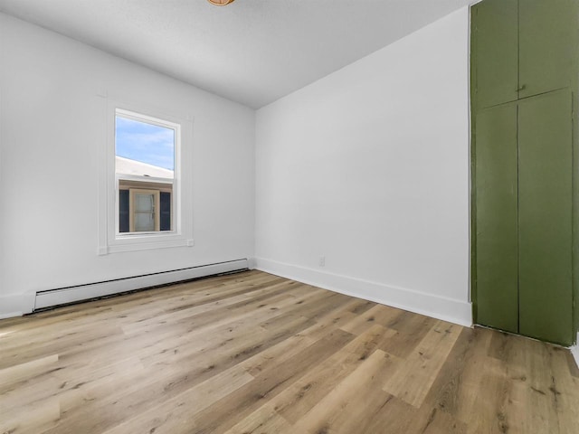 spare room featuring a baseboard radiator and light wood-type flooring