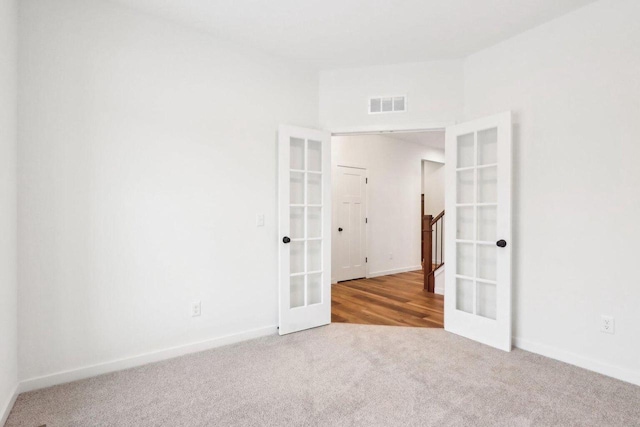 carpeted spare room featuring french doors