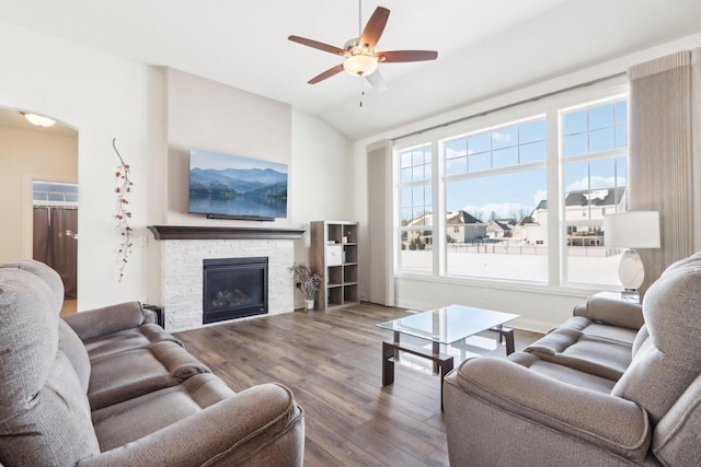 living area with arched walkways, a ceiling fan, wood finished floors, vaulted ceiling, and a fireplace