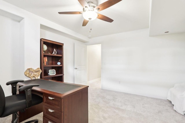 office with baseboards, built in features, ceiling fan, and light colored carpet