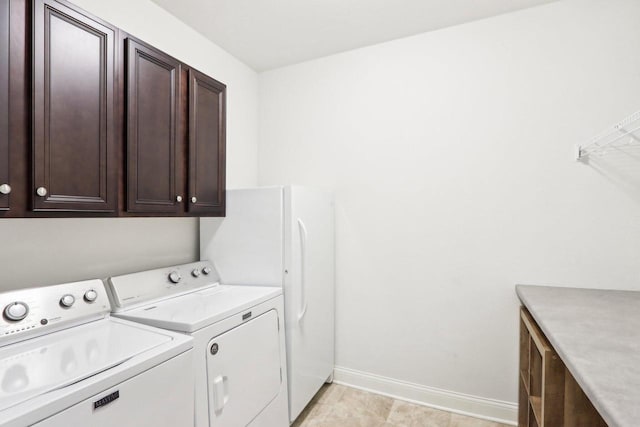 clothes washing area featuring cabinet space, independent washer and dryer, and baseboards