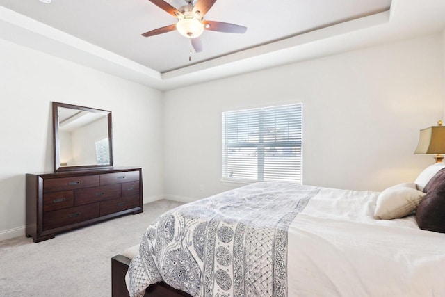 bedroom with baseboards, a tray ceiling, a ceiling fan, and light colored carpet