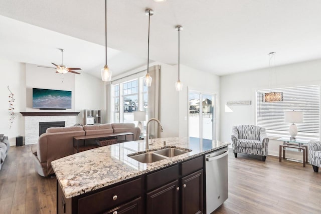 kitchen featuring a kitchen island with sink, a fireplace, a sink, open floor plan, and dishwasher