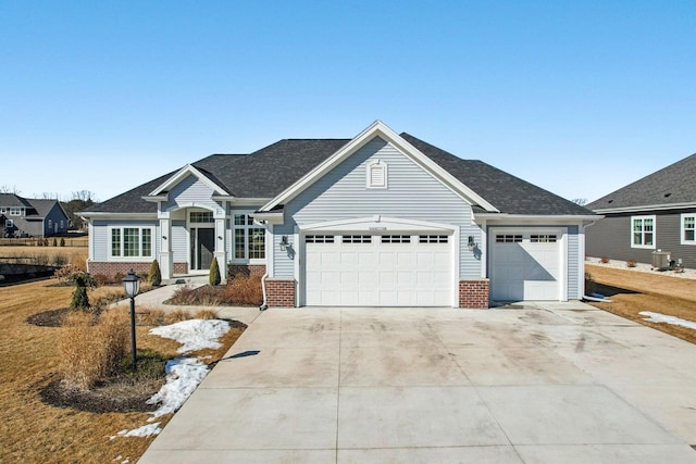 view of front of home featuring an attached garage, central AC unit, concrete driveway, and brick siding