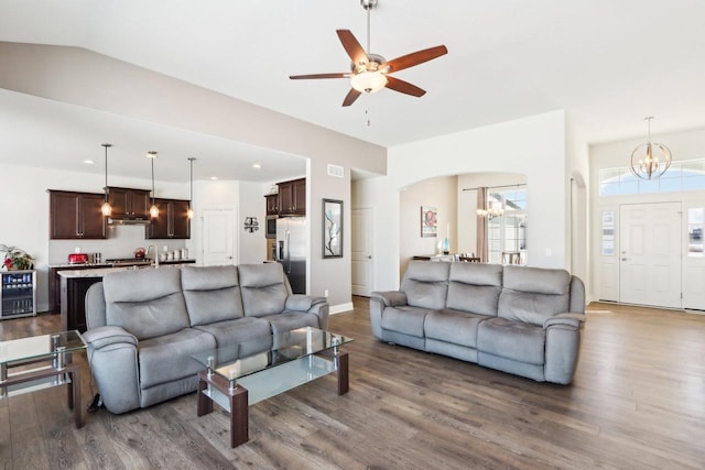 living room with wine cooler, arched walkways, vaulted ceiling, and dark wood-style flooring