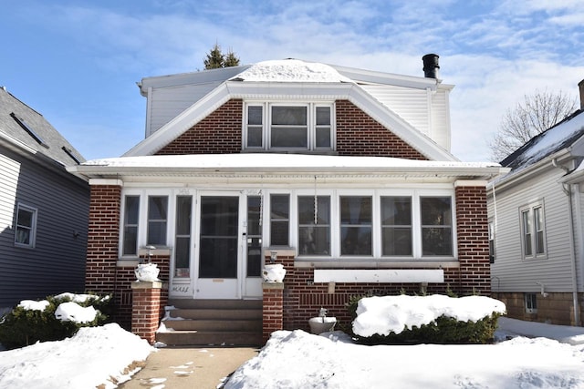 snow covered house with entry steps and brick siding