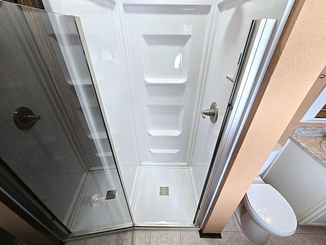 bathroom featuring vanity, toilet, a shower with shower door, and tile patterned floors