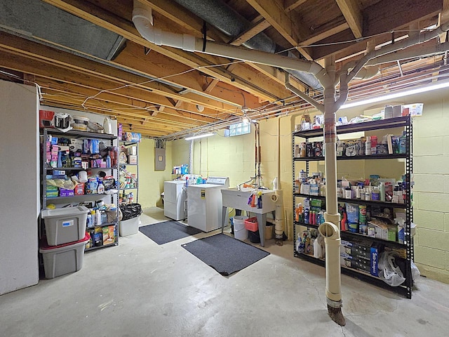 basement featuring washing machine and dryer, electric panel, and sink