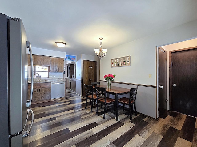 dining area with a notable chandelier, sink, and dark wood-type flooring