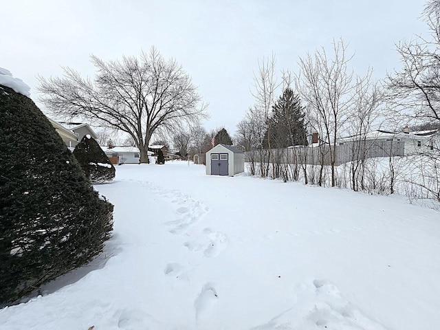 snowy yard featuring a storage unit