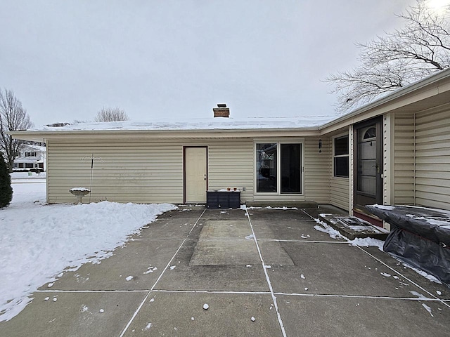 snow covered back of property featuring a patio area