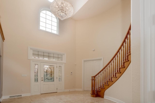 entrance foyer featuring stairs, a towering ceiling, an inviting chandelier, baseboards, and visible vents