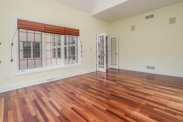 unfurnished room featuring wood finished floors, baseboards, and visible vents