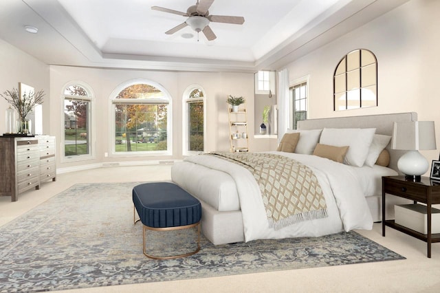 bedroom featuring ceiling fan, light colored carpet, and a tray ceiling