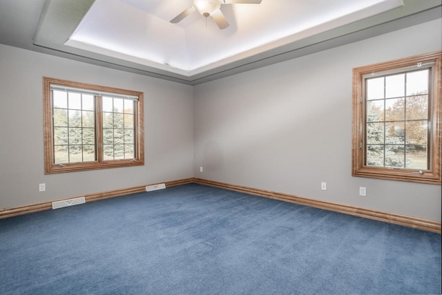 spare room with ceiling fan, a raised ceiling, visible vents, and carpet flooring