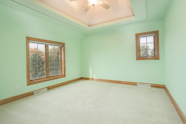 unfurnished room with a raised ceiling, carpet, and visible vents