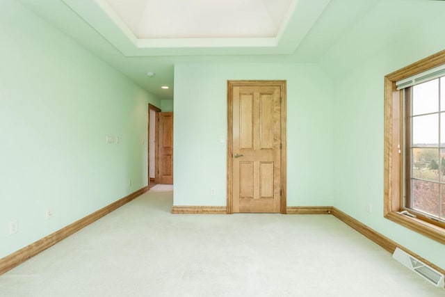 unfurnished bedroom with carpet, visible vents, a raised ceiling, and baseboards