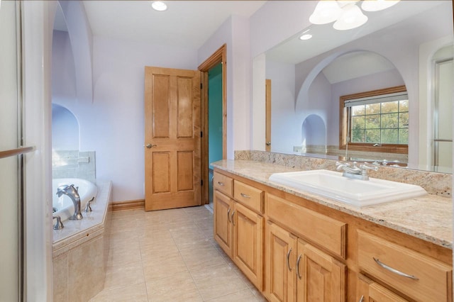 full bath with tile patterned flooring, baseboards, a washtub, and vanity