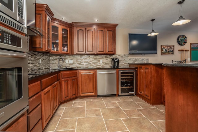 kitchen featuring pendant lighting, beverage cooler, stainless steel appliances, dark countertops, and glass insert cabinets