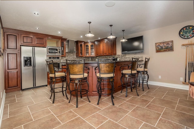 kitchen featuring appliances with stainless steel finishes, backsplash, dark countertops, a kitchen breakfast bar, and glass insert cabinets