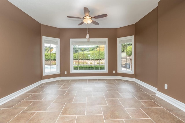 spare room with ceiling fan, baseboards, and light tile patterned floors