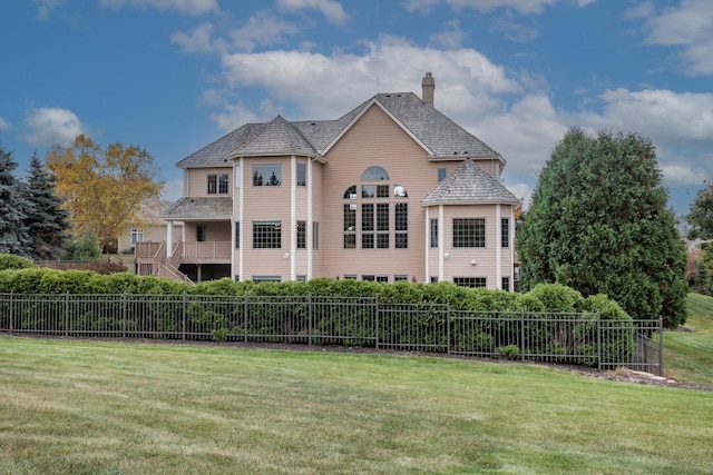 back of house with stairway, a lawn, fence, and a chimney