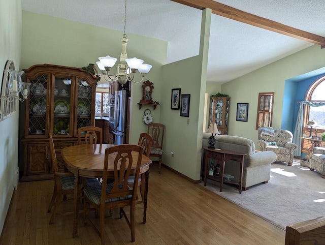 dining area featuring a notable chandelier, lofted ceiling with beams, a healthy amount of sunlight, and hardwood / wood-style flooring