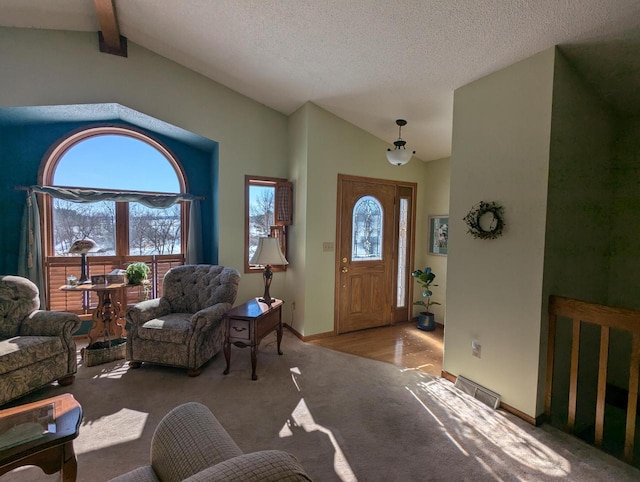 entryway with a textured ceiling, light carpet, and vaulted ceiling with beams