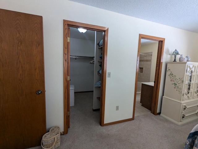 carpeted bedroom featuring a spacious closet, a closet, connected bathroom, and a textured ceiling