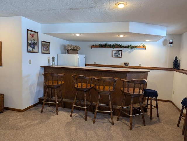 bar featuring a textured ceiling, carpet, and white refrigerator