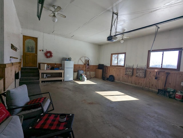 garage featuring wood walls, white fridge, and a garage door opener