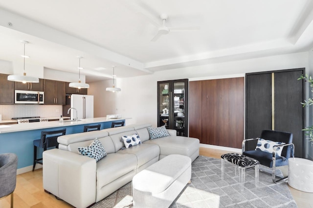 living room featuring ceiling fan, sink, and light hardwood / wood-style flooring