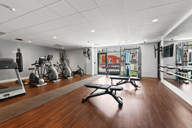 exercise room featuring a paneled ceiling and hardwood / wood-style flooring