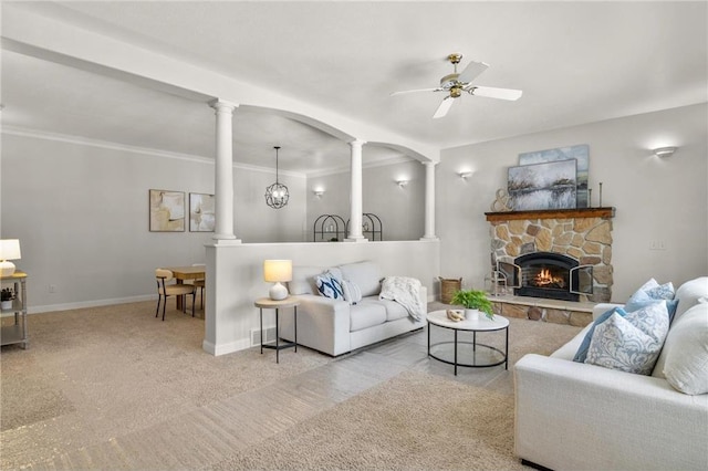 living room featuring light colored carpet, a fireplace, a ceiling fan, baseboards, and decorative columns