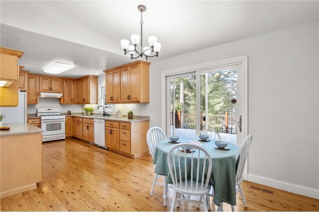 kitchen with white appliances, light wood-style floors, pendant lighting, and light countertops