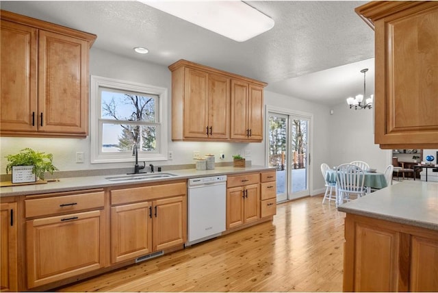 kitchen with white dishwasher, pendant lighting, light countertops, and a sink