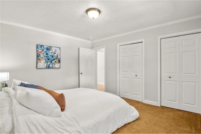 bedroom with baseboards, carpet flooring, two closets, and crown molding