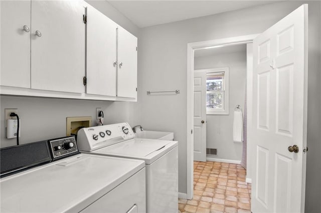 clothes washing area featuring cabinet space, a sink, washer and clothes dryer, and baseboards