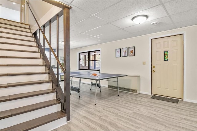 rec room with light wood-type flooring, baseboards, and a paneled ceiling